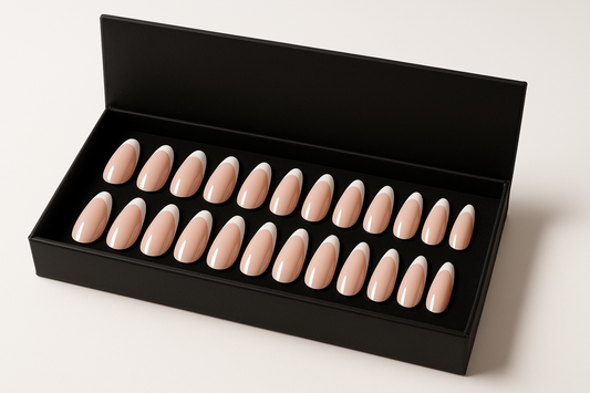 Professional product photography of a set of 24 classic French manicure press-on nails, white tips on nude pink base, elegant oval  shapes arranged in a luxury black box, clean white background, high-end beauty product styling"