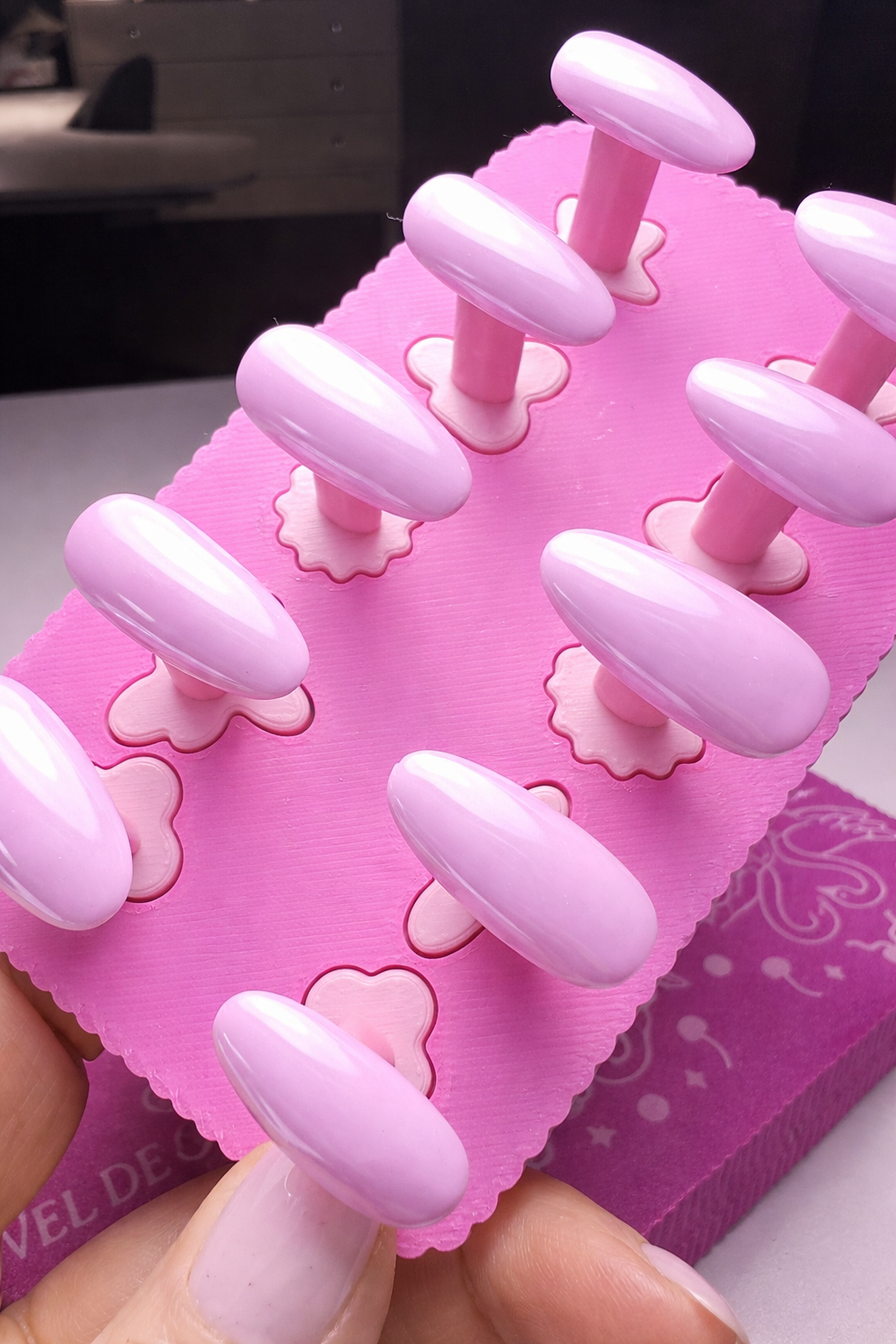 Pale pink press on nails with chrome highlights on a pink nail stand 