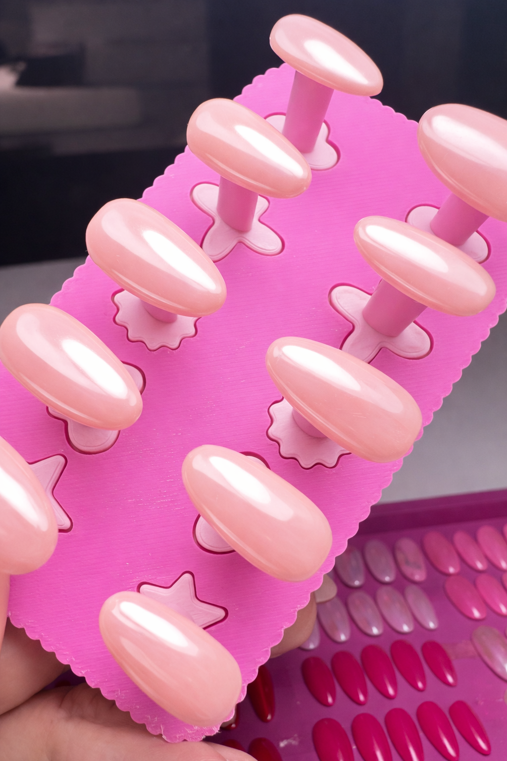 Set of 10 nude press on nails with chrome and glossy top coat. On a pink nail stand 